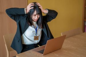PCの前で頭を抱える女性